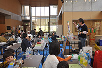 室内の広間で親子や子供たちが工作や体験活動を行っている写真