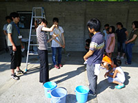 屋外の作業スペースで参加者たちが協力して実験や作業を行っている写真