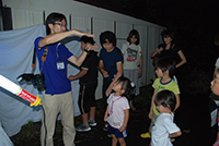 暗い室内で講師が子供たちに生き物の特徴を説明している写真