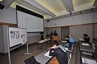 会議室で参加者たちが机に向かって研究発表や講義を受けている写真