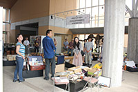 施設のロビーで職員と参加者たちが展示や物品を囲んで交流している写真