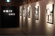 暗い照明の部屋に様々な写真が展示されている様子の写真