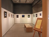 室内の三方面の白い壁に額縁に入った写真が飾られている写真