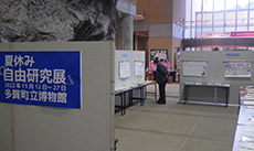 展示会場内でパネル展示を来場者が見ている様子の写真