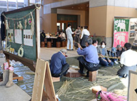 床に座りしめ縄を作成する数人の男性たちの写真