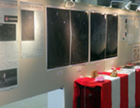 展示会場の壁面に写真作品と展示台が並んでいる様子の写真