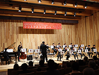 滋賀学園中学校高等学校ジャズオーケストラ部の生徒たちがステージ上で様々な楽器を使って演奏している様子の写真