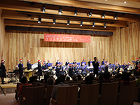 サンタ帽を被った近江高等学校吹奏楽部の生徒たちがステージ上で様々な楽器を使って演奏している様子の写真