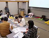 プロジェクターが設置されている部屋で着席してサインボードを作る参加者たちの写真