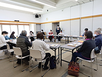 部屋の中で着席し向かい合って協議している複数人の男女の写真