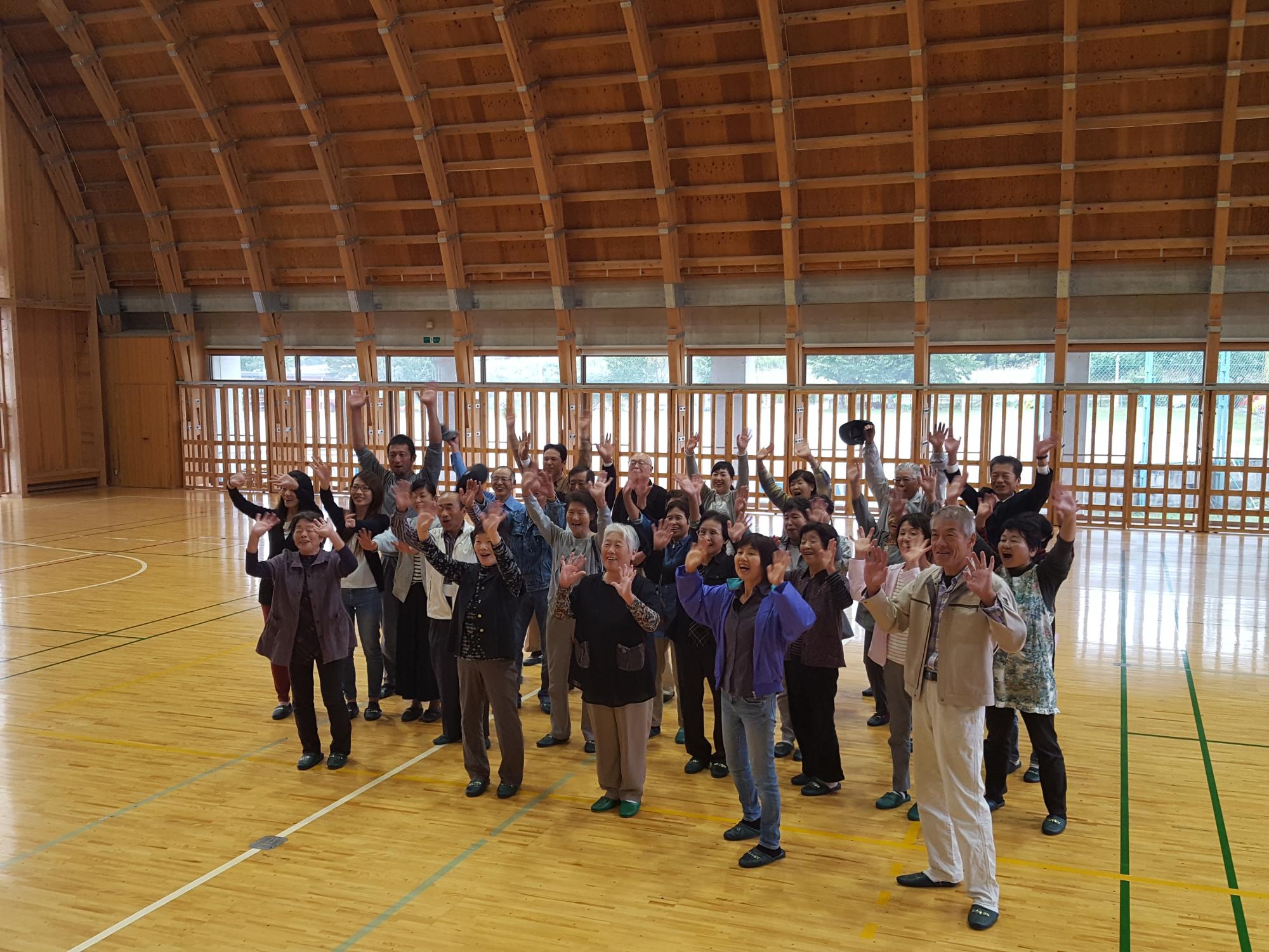 体育館で両手を上に高く挙げている人たちの写真