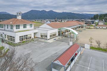 園庭と駐車場と赤レンガ色をした屋根の建物がある敷地の写真