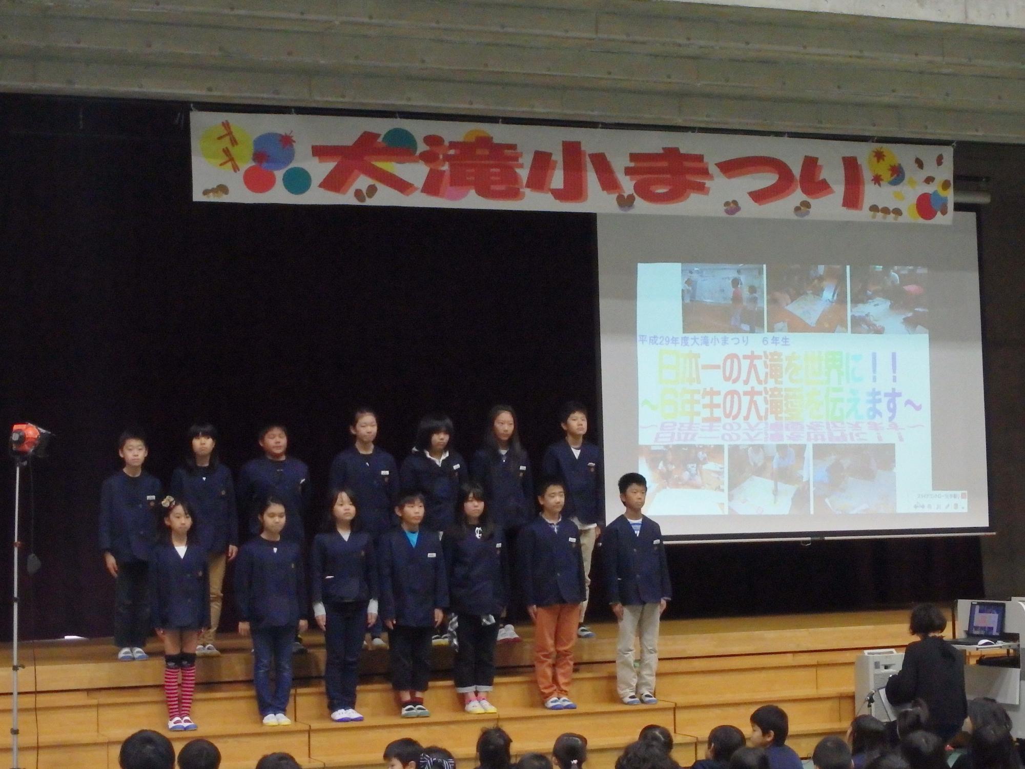 「大滝小まつり」と書かれた舞台に2列で並んでいる児童たちの写真