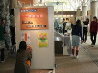 ホワイトボードに展示された展示物を鑑賞する女性たちの写真