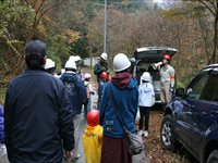 山道の駐車スペース付近で親子や参加者たちが集まって移動している写真