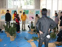 室内で参加者たちが正月飾りを囲んで門松づくりをしている写真