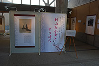 暗い照明の室内に大型のパネルが複数展示されている様子の写真