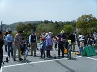 屋外の広場で親子や参加者たちが受付周辺に集まってイベント開始を待っている写真