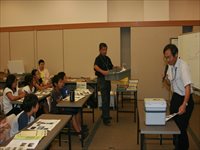 会議室で職員が資料を配りながら参加者たちに説明をしている写真