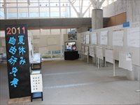 2011夏休み自由研究展と書かれたパネルと様々な作品が飾られている展示風景の写真