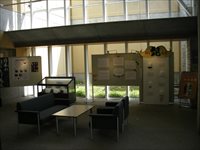 暗い照明の部屋にホワイトボードやガラス張りのショーケースが設置された県立大学ミニ博物館展の写真