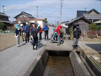 用水路の周辺で参加者たちが列になって地域散策や現地観察をしている写真