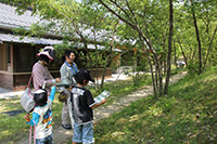 緑生い茂る日本家屋の前に立つ大人子供それぞれ2人ずつの写真