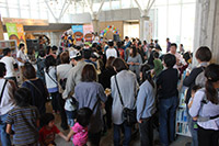 ガラス張りの屋内の広場に集まる大勢の人々の写真