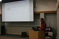 スクリーンに資料を投影して説明する男性の写真