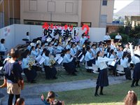 屋外ステージ前で大勢の生徒たちが楽器を持って演奏している写真