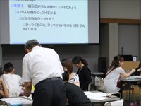 会議室で参加者たちが机に向かい資料を見ながら自由研究の講義を受けている写真