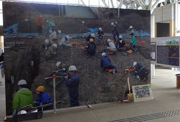 展示会場で発掘調査の様子を写した大型パネルが展示されている写真