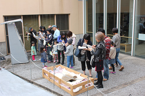 建物の中庭で親子や大人たちが資料を見ながら観察に参加している写真