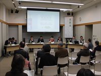 会議室で登壇者と参加者が向かい合い意見交換を行っている座談会の写真