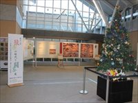 ホールの中央に置かれたクリスマスツリーと壁に貼られた展示物の写真