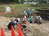 造成地の作業エリアで親子が地面を掘りながら発掘活動をしている写真