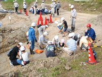 造成地の区画内で親子や地域の大人たちが集まって発掘体験をしている写真