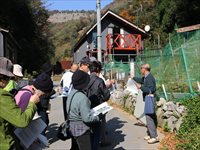 山間部の建物前で参加者たちが説明を聞きながら見学している写真