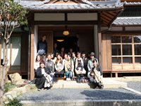 伝統的な和風建築の玄関前で参加者たちが集合して記念撮影をしている写真
