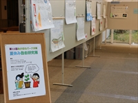 入口の茶色い案内板と壁に自由研究作品が展示されている写真