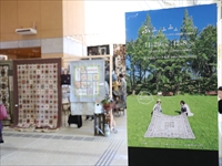 青空と芝生と青々とした木々が写されている大きなパネルがホールに置かれている写真