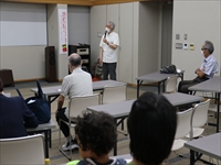 研修室で講師が前に立ち参加者たちに説明をしている写真