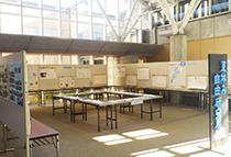 展示会場の中央にテーブルと掲示パネルが配置された自由研究展の全体写真