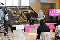 博物館のロビーの特設ステージで登壇者がトークイベントを行い来場者が骨格展示の前で聞いている写真