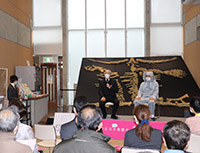 会場前方で登壇者と聞き手が向かい合い対談をしている写真