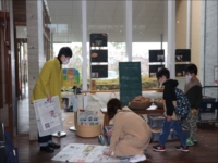 部屋の中で飾られた写真を観覧する複数の子供と大人たちの写真