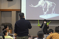 スクリーンにゾウの映像を映し講師が子どもたちに説明している講演会の写真