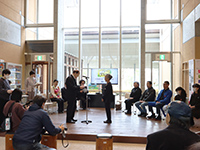 ロビーで参加者が円になって座り司会者の進行で意見交換している写真