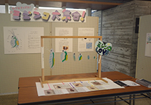 展示スペースで児童向けの工作作品と解説資料が並べられている写真