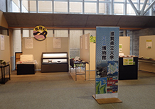 展示会場全体を写した複数の展示ブースと案内スタンドの写真